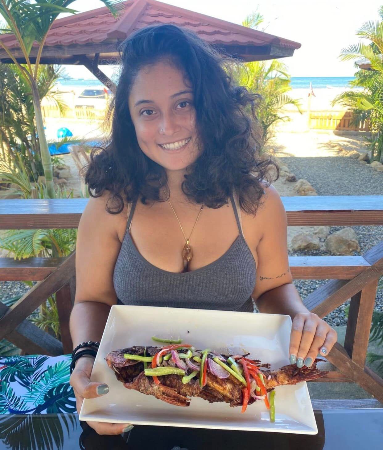 A woman is holding a plate of food and smiling