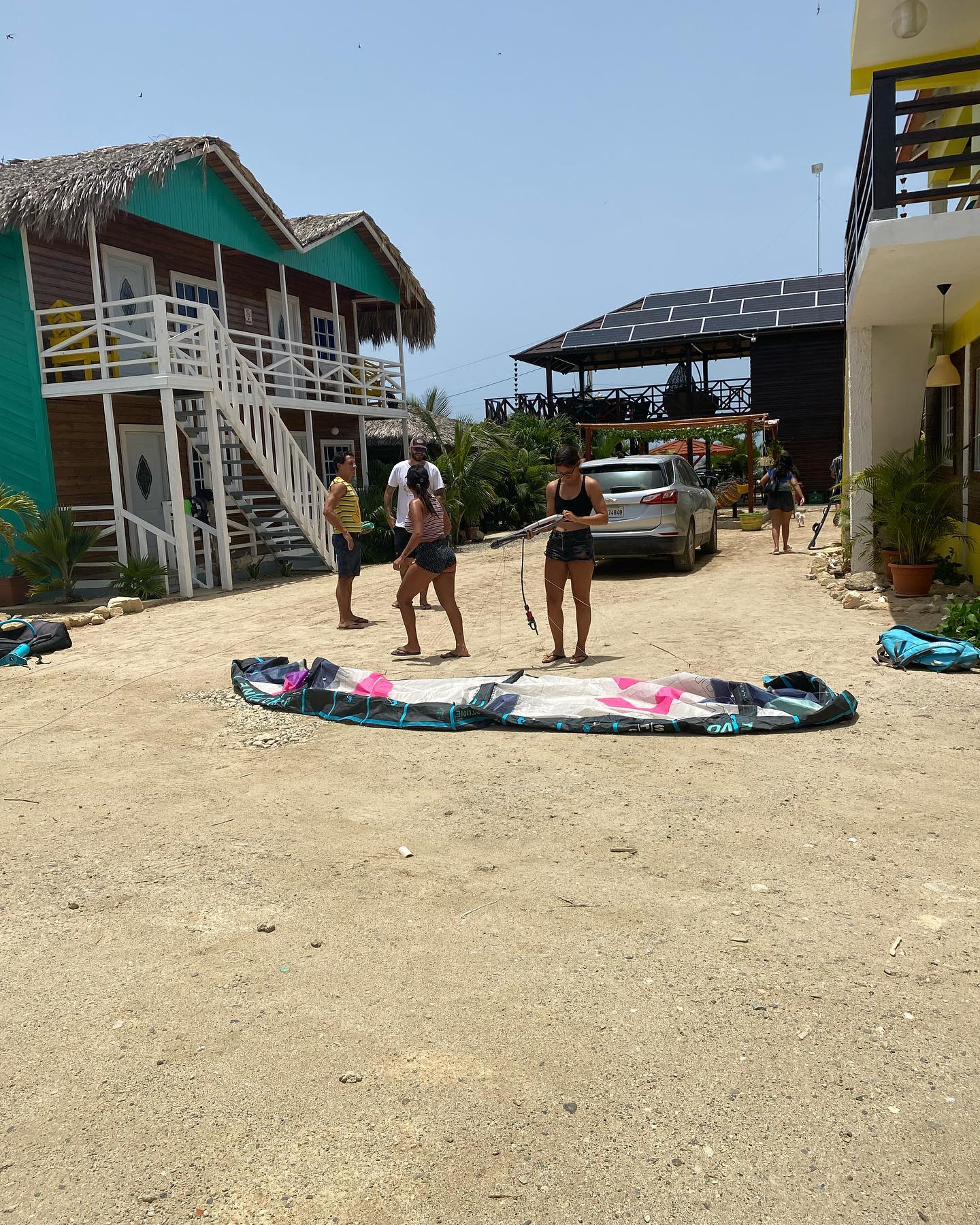 A group of people standing around a kite in a dirt area
