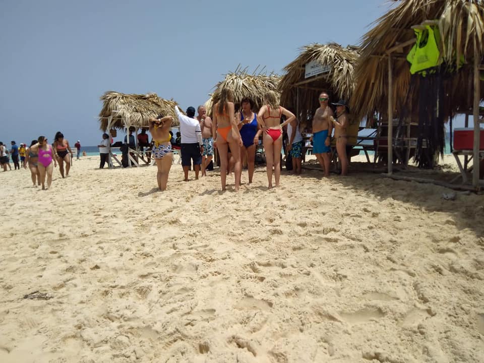 A group of people are standing on a sandy beach.