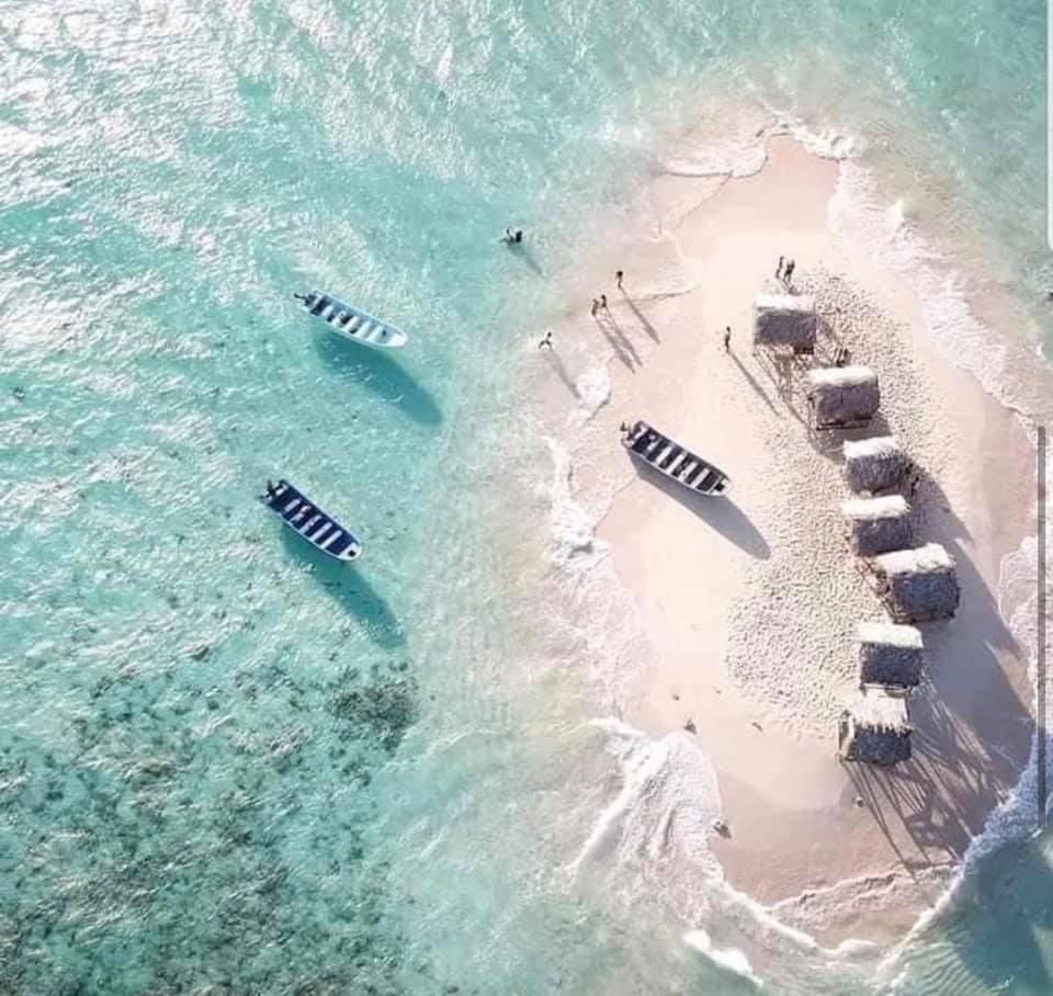 An aerial view of a small island in the middle of the ocean with boats on it.