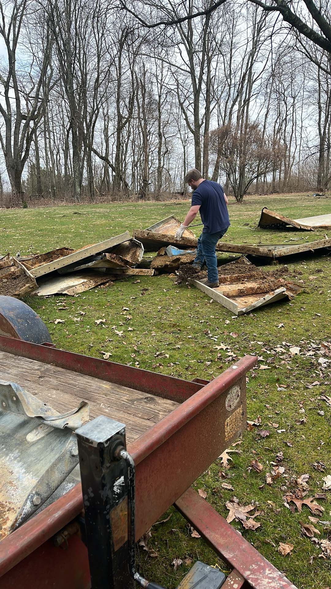 A man is standing in a field next to a trailer.