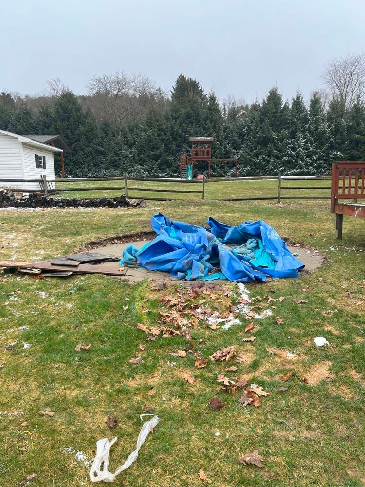 A blue tarp is covering a hole in the ground in a yard.