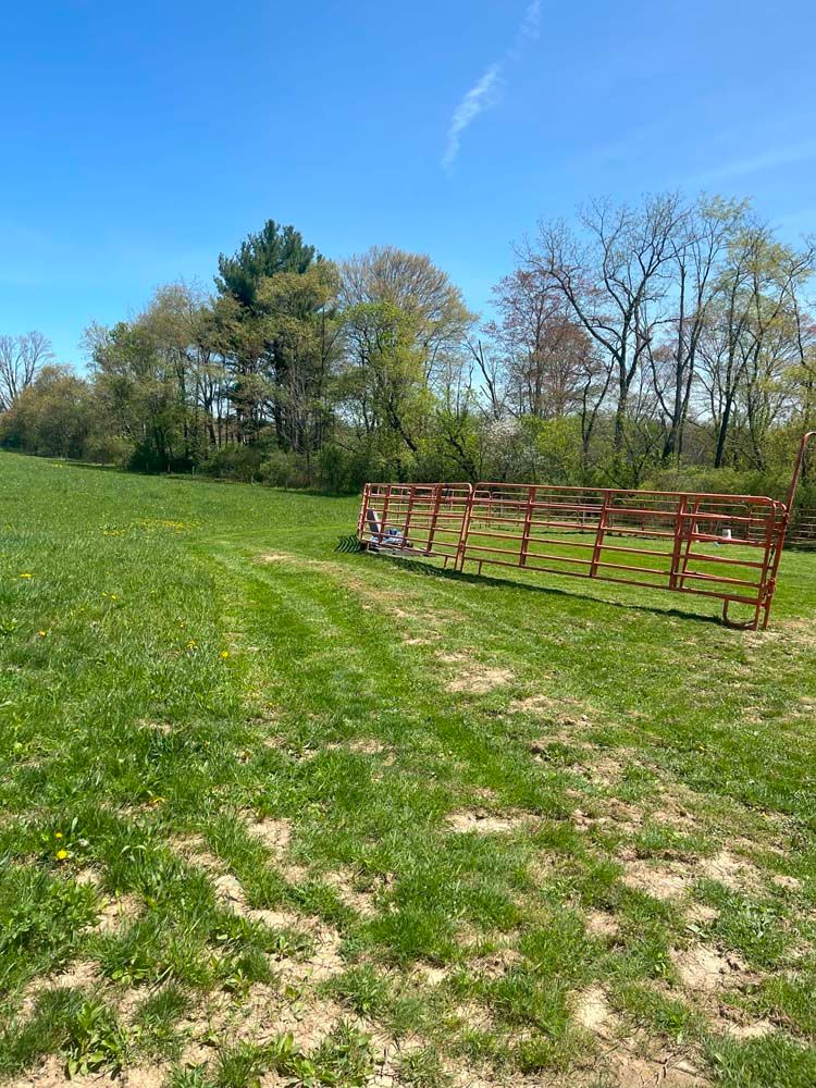 There is a wooden fence in the middle of a grassy field.