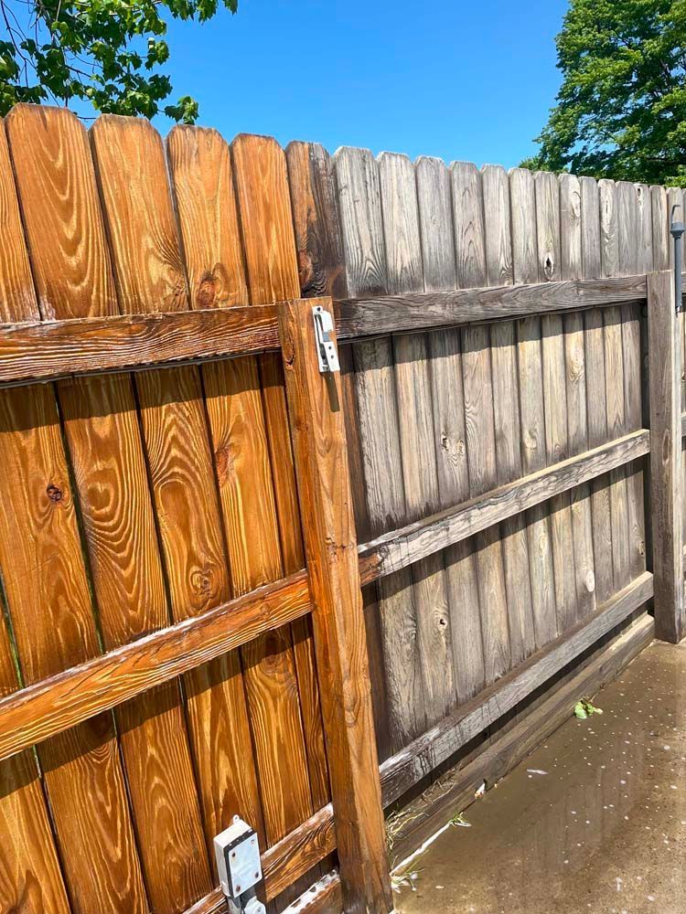 A wooden fence with a gate and a blue sky in the background.