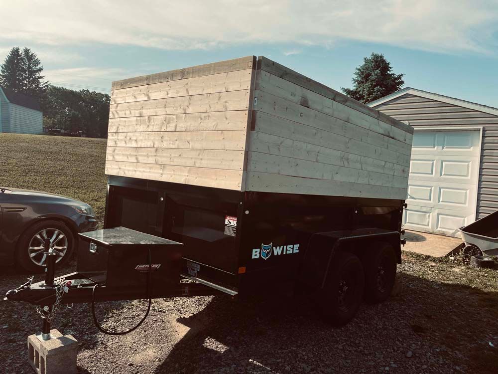 A car is parked next to a trailer with a box on it.