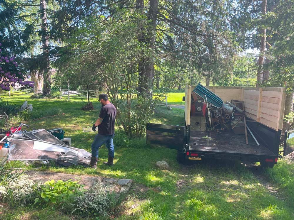 A man is standing next to a dump truck in a yard.
