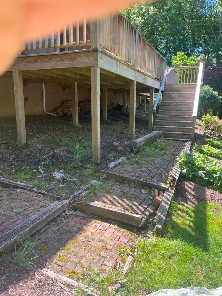 A wooden deck with stairs leading up to it in a backyard.