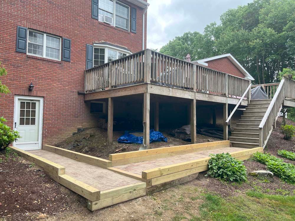 A brick house with a wooden deck and stairs in front of it.