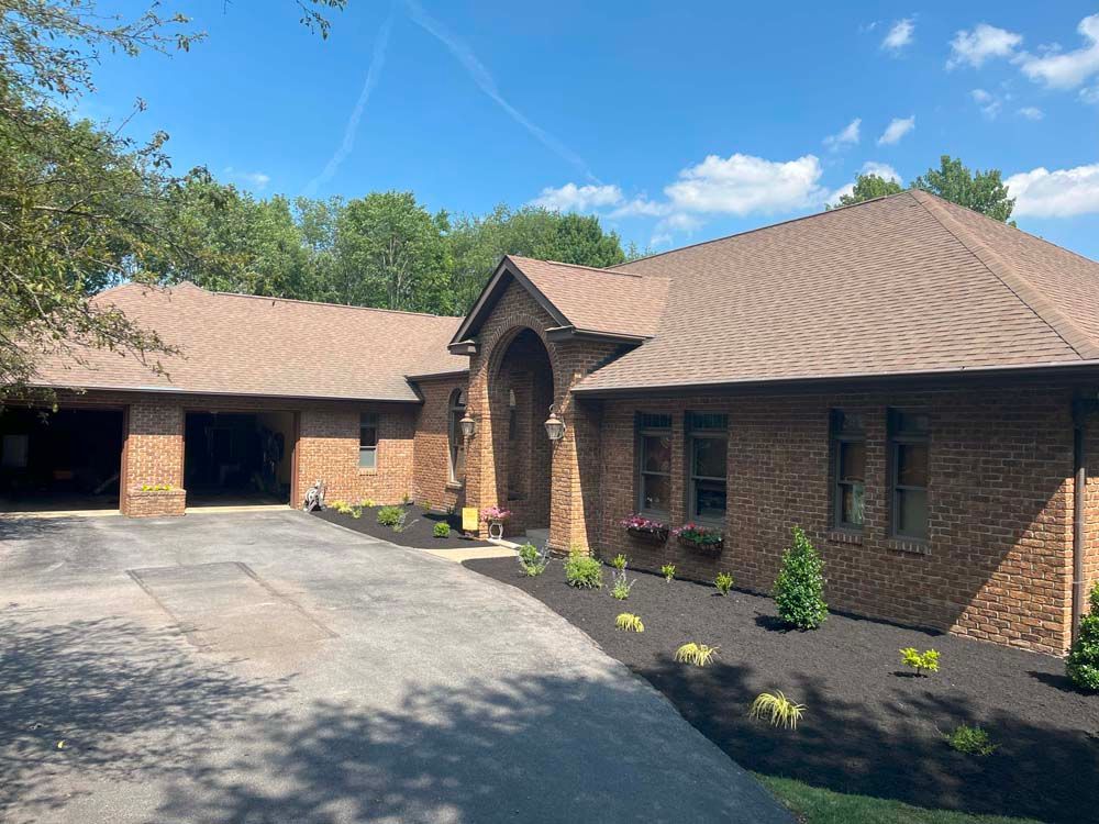 A large brick house with a brown roof and a driveway.