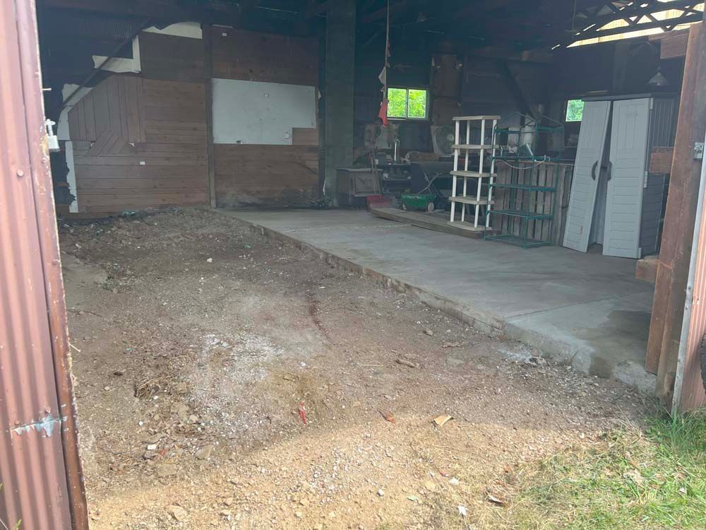 The inside of a garage with a lot of dirt and a concrete floor.