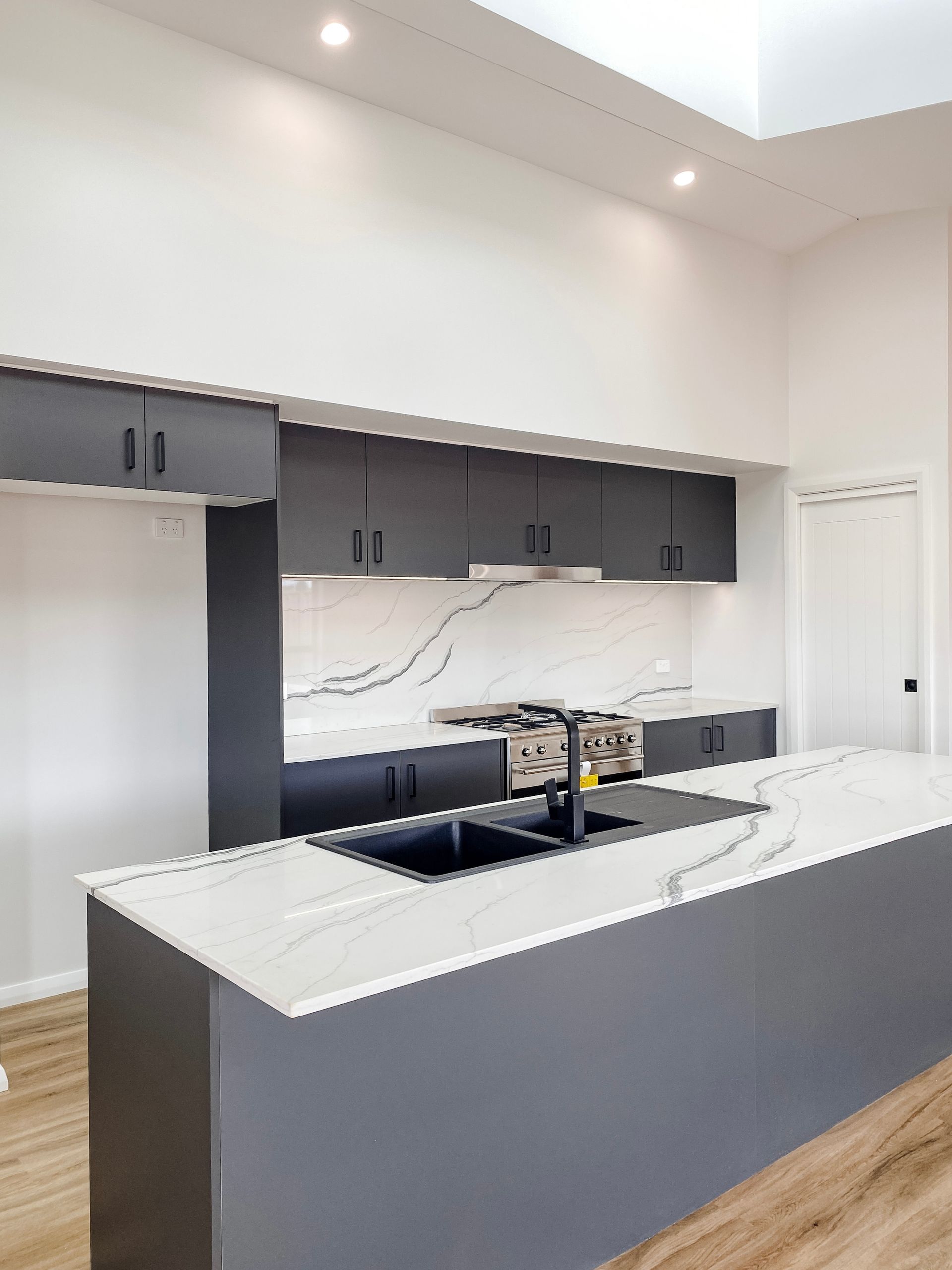 Modern White Kitchen Featured Black Cabinets — Kitchen Renovations in Dubbo, QLD