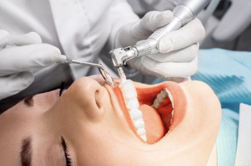 A woman is getting her teeth cleaned by a dentist.