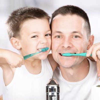 A man and a child are brushing their teeth together
