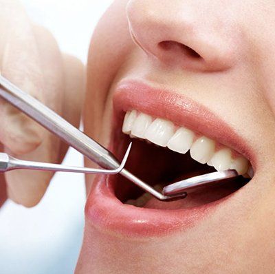 A woman is getting her teeth examined by a dentist