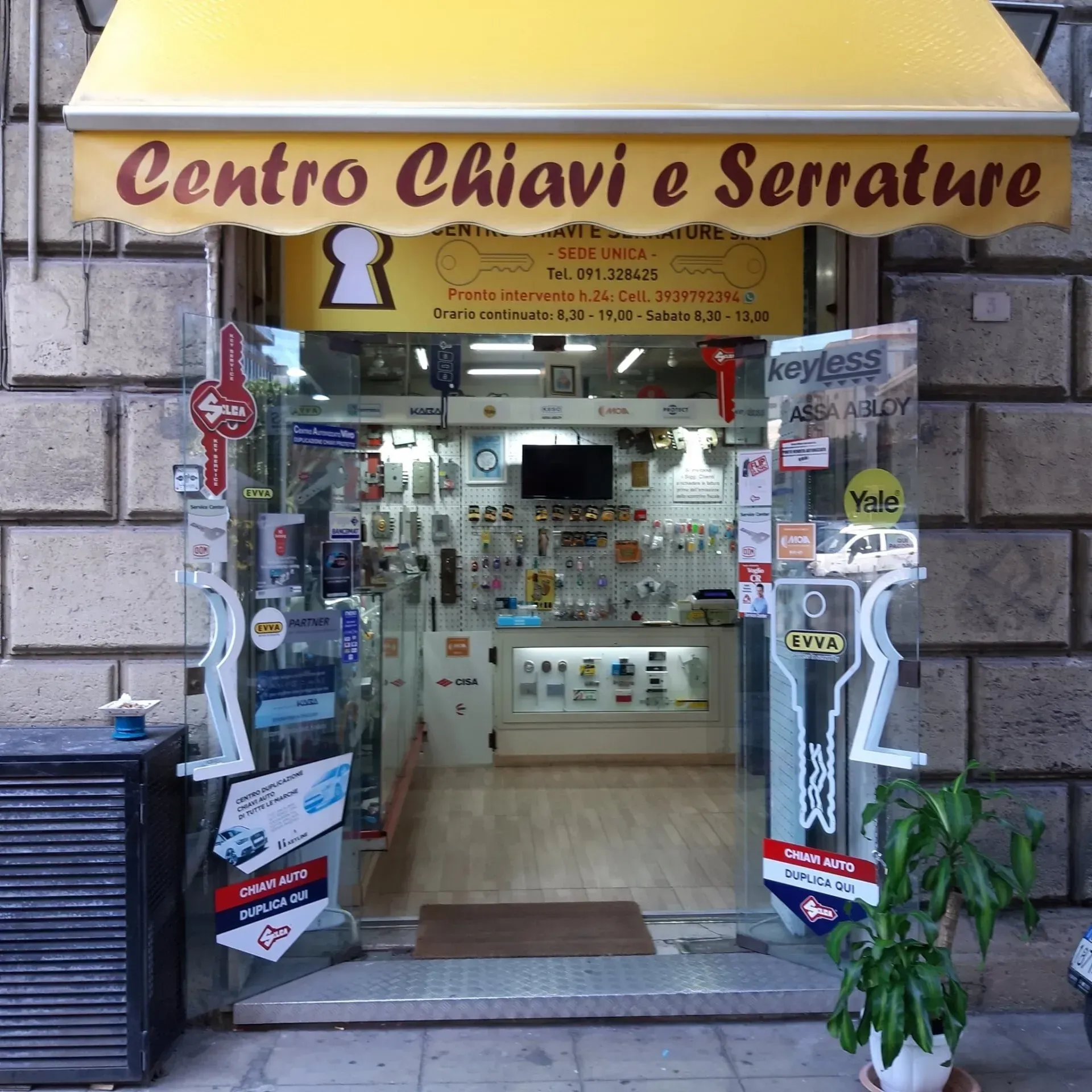 Un negozio di fabbro con una tenda da sole gialla, che offre servizi di chiavi e serrature.