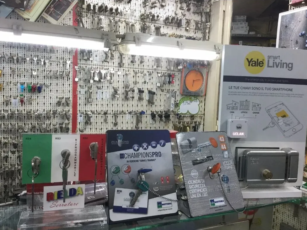 Un espositore per negozio di chiavi con una parete di chiavi, brochure sulle serrature e un sistema di sicurezza Yale Living.