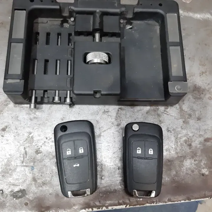 Programmatore di chiavi per auto con due portachiavi neri su una superficie metallica.