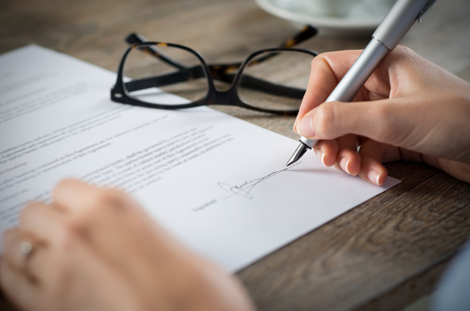 A person is writing on a piece of paper with a pen.