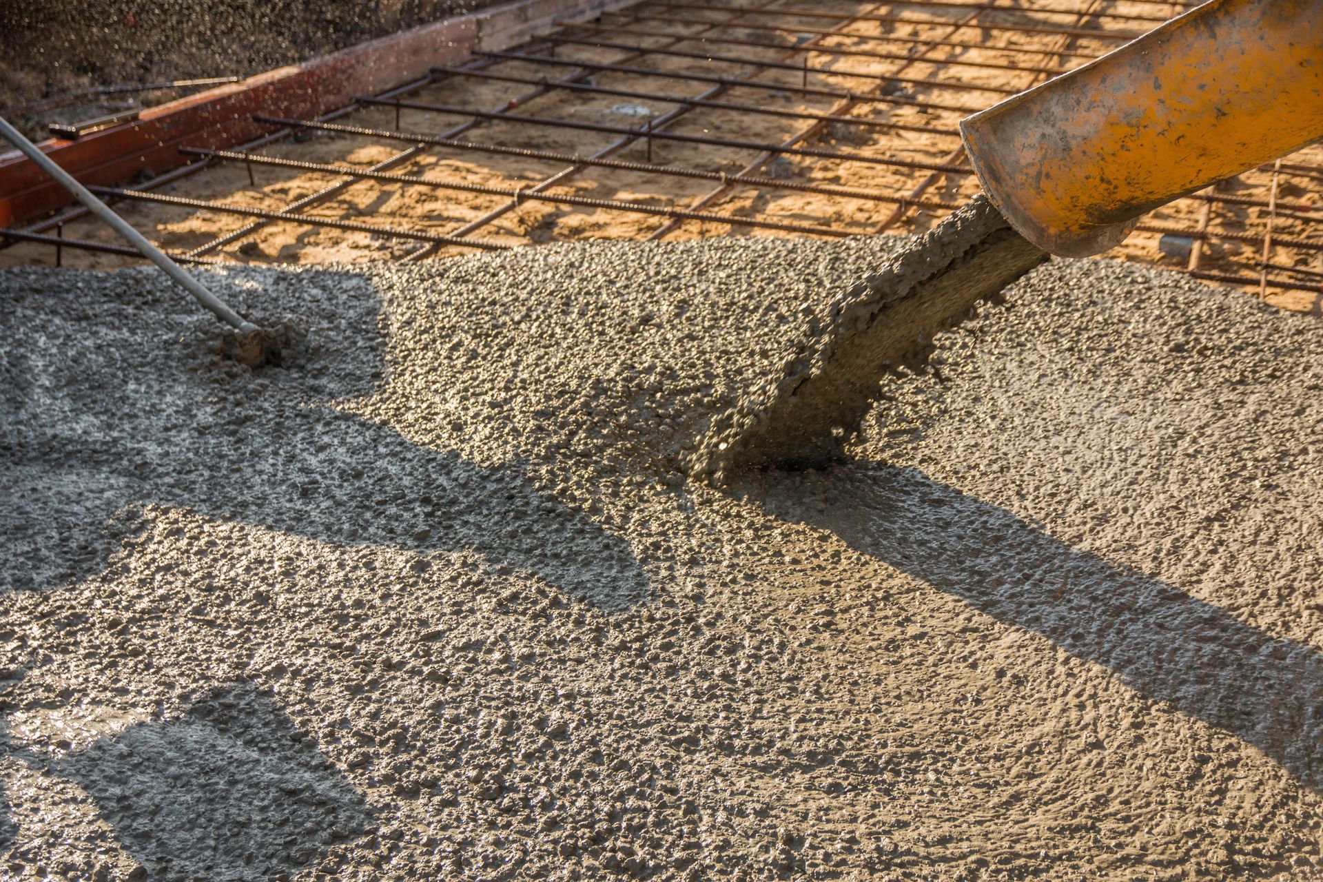 A concrete pump is pouring concrete on a brick sidewalk.
