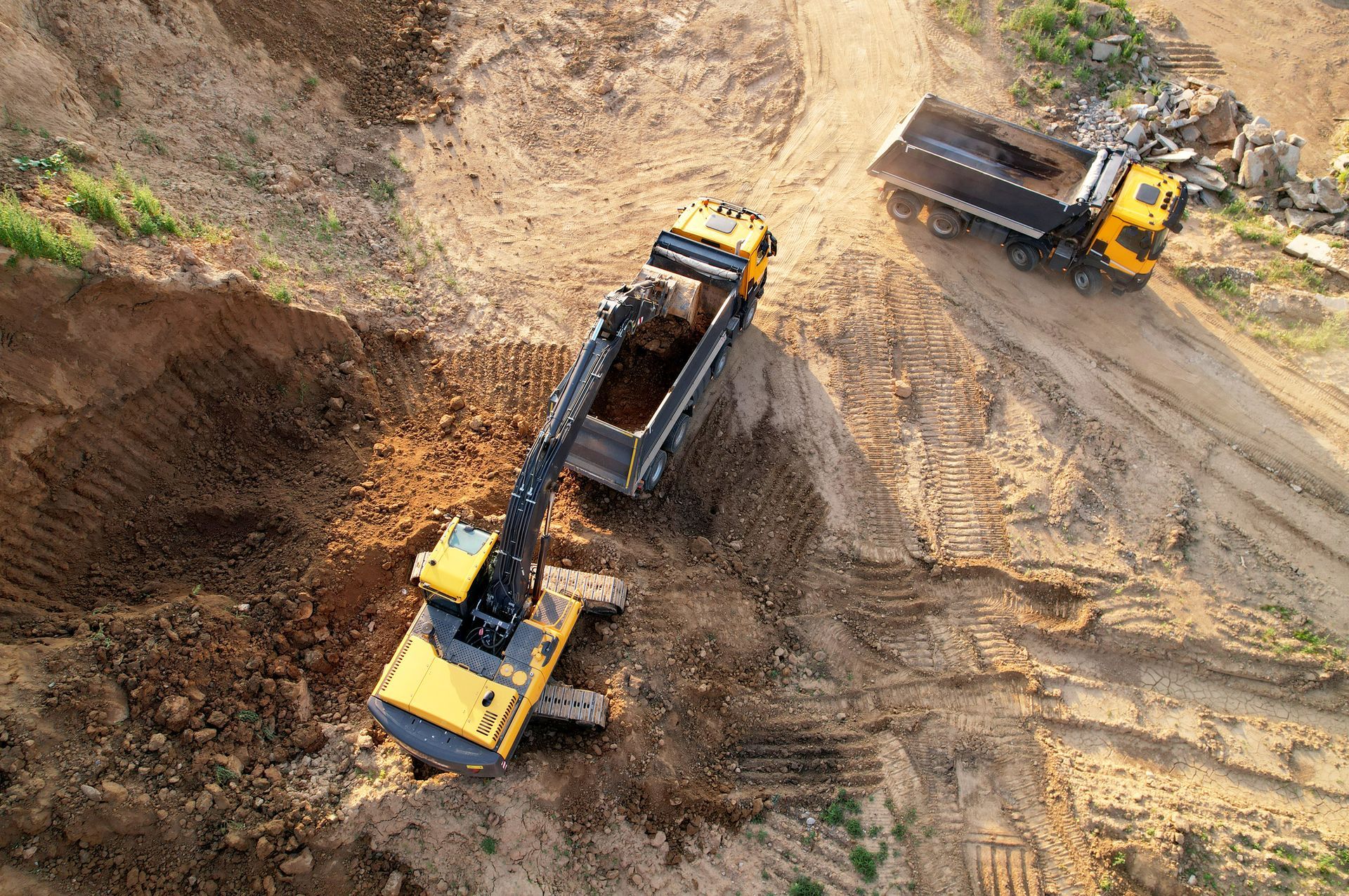 An aerial view of a construction site with a bulldozer and a dump truck.