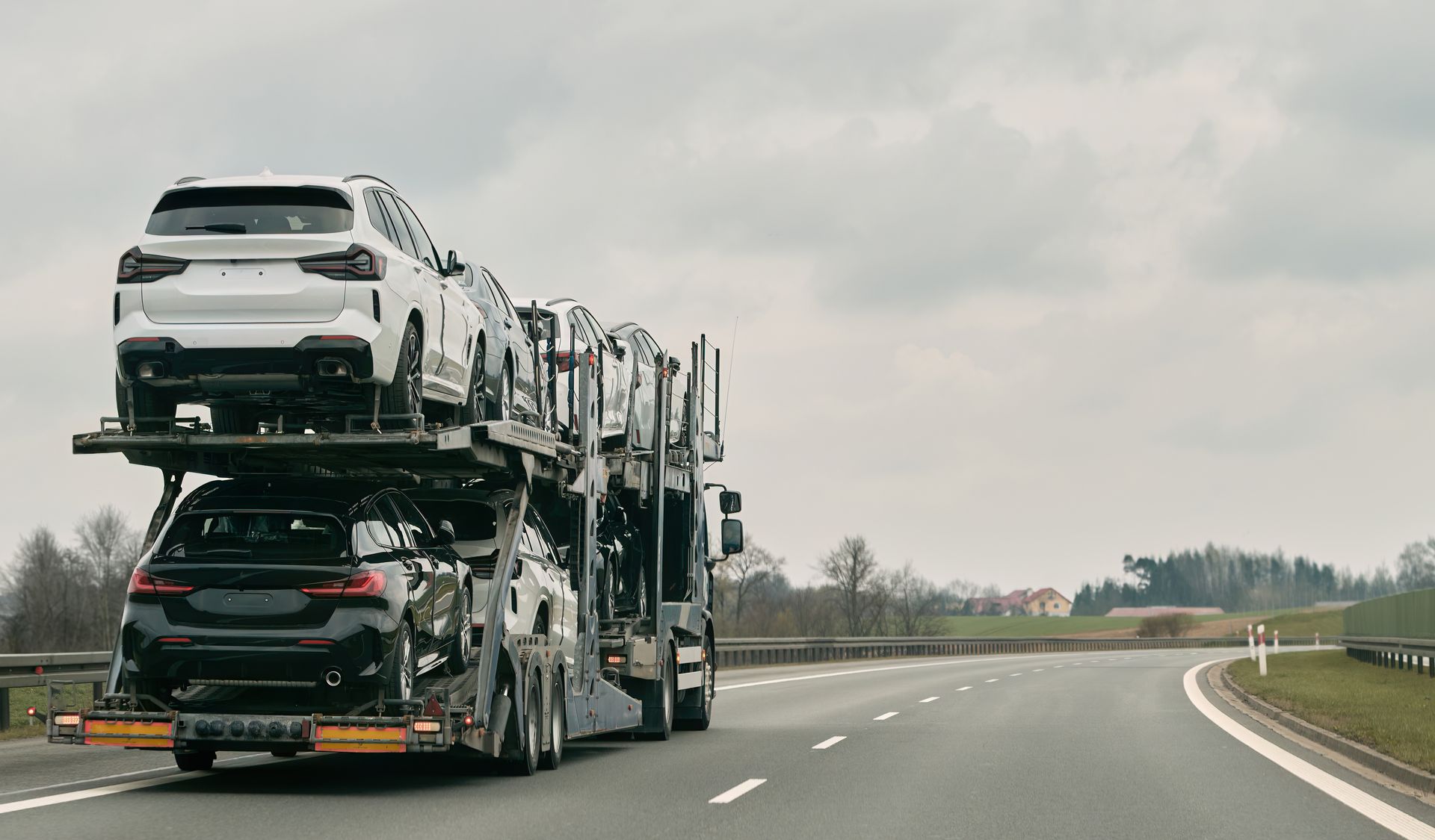 A car transporter is driving down a highway carrying a stack of cars.