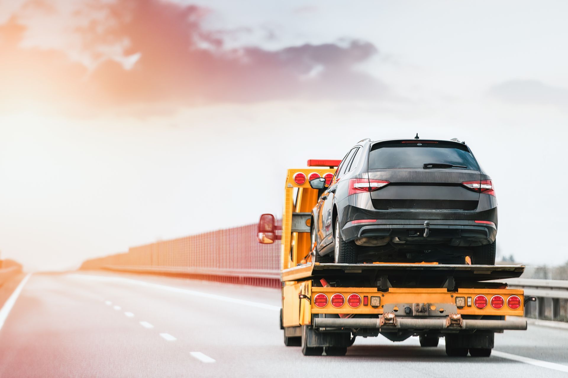A car is being towed down a highway by a tow truck.