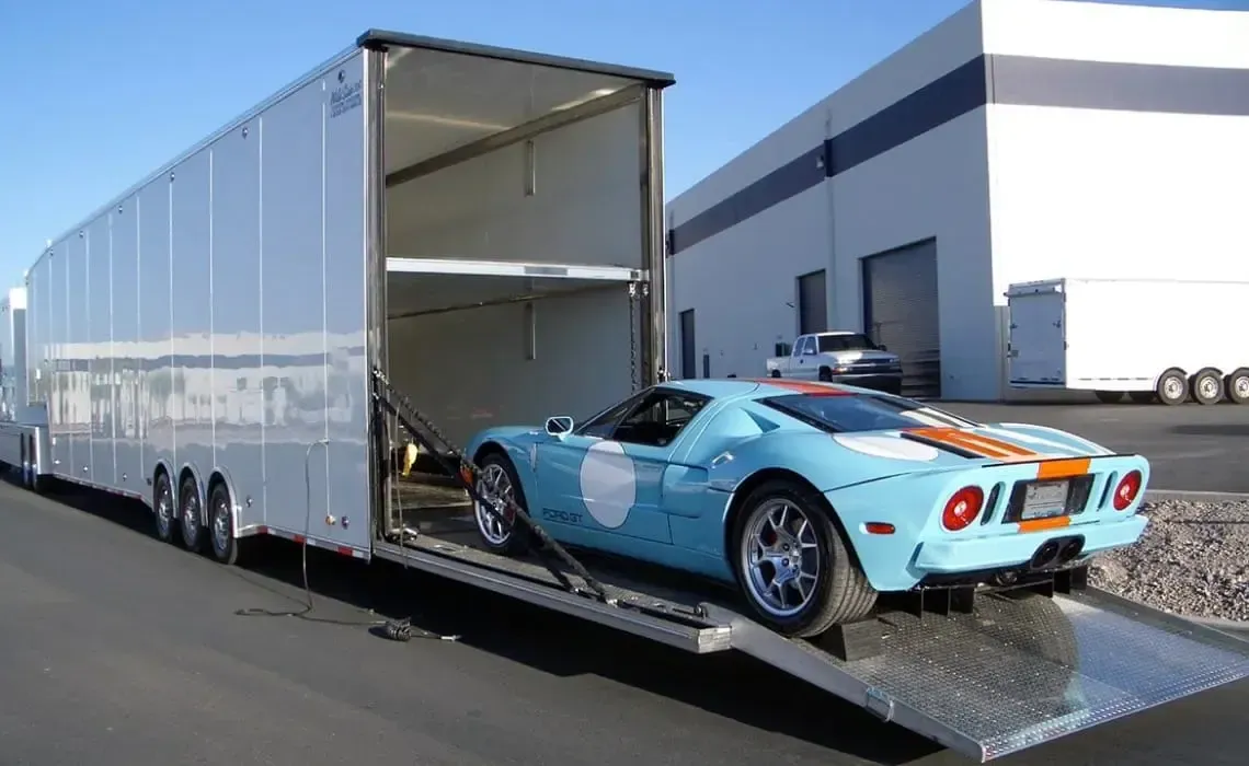 A blue sports car is being loaded into a trailer