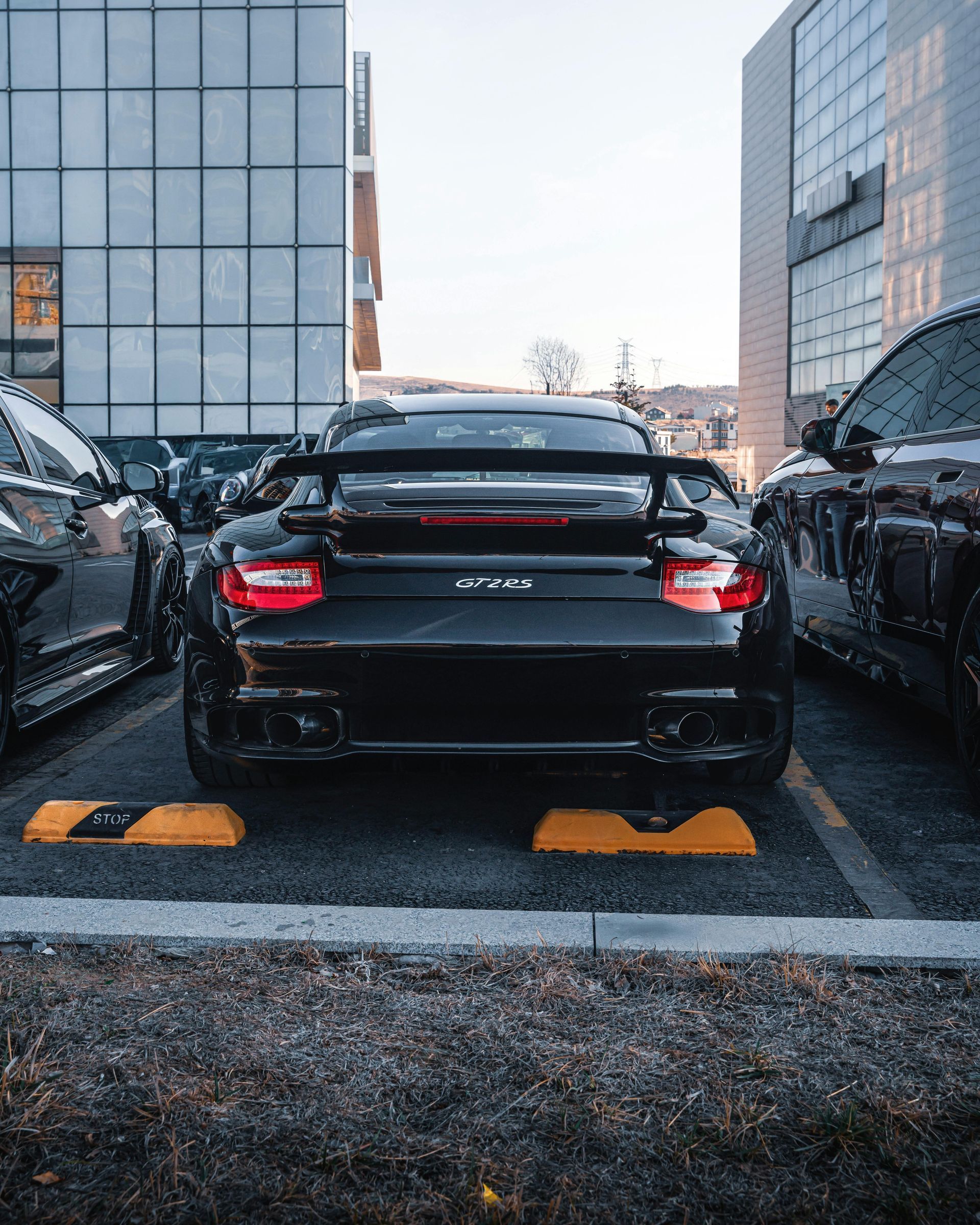 A black sports car is parked in a parking lot in front of a building.