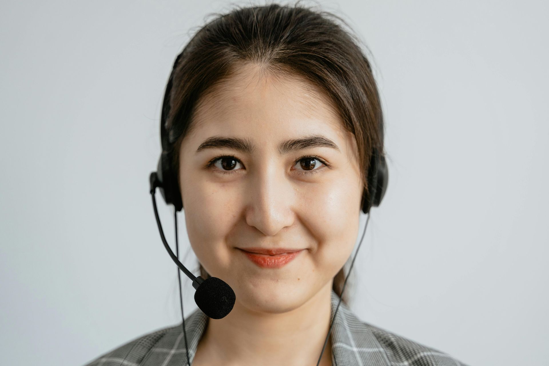 A woman is wearing a headset and smiling.