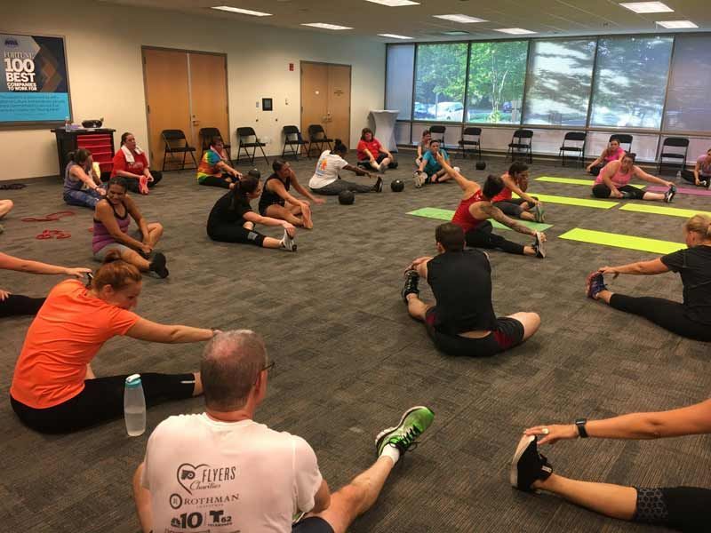 A group of people are doing stretching exercises in a room.