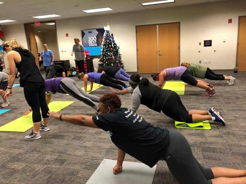 A group of people are doing push ups on yoga mats in a room.