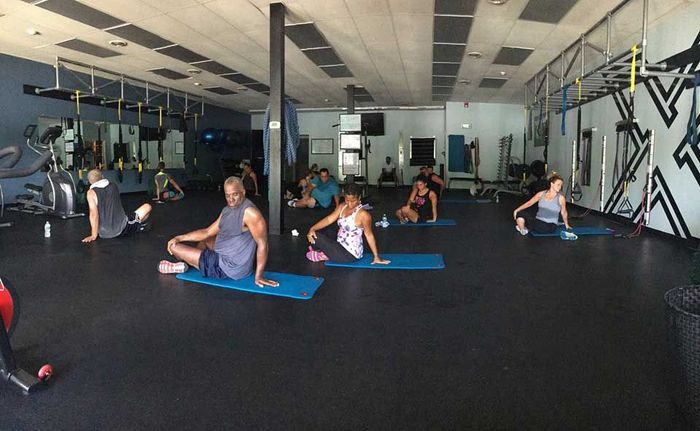 A group of people are sitting on yoga mats in a gym.