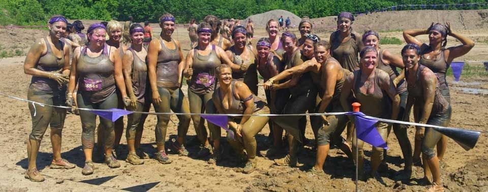 A group of people covered in mud are posing for a photo