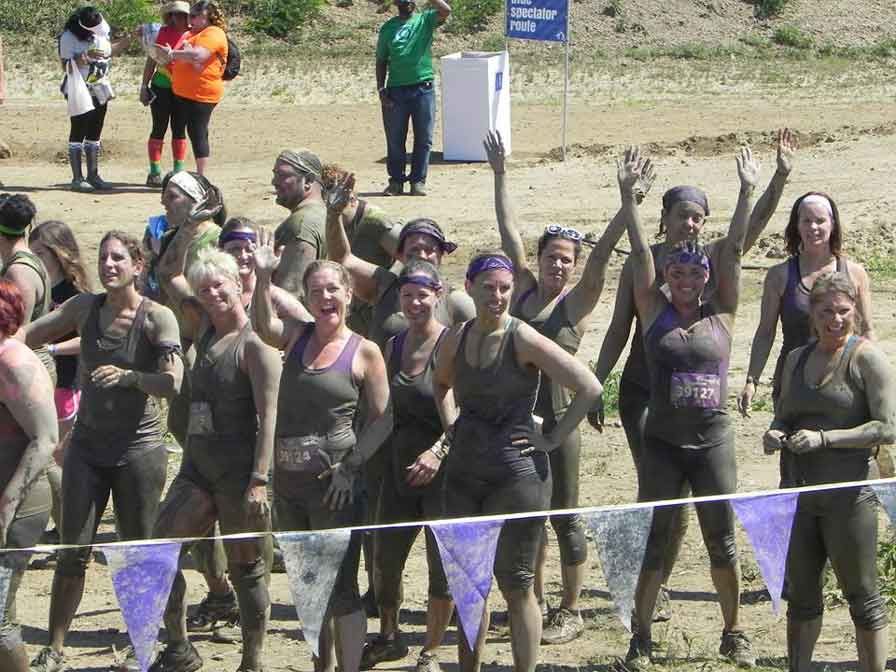 A group of women are standing in the mud with their arms in the air