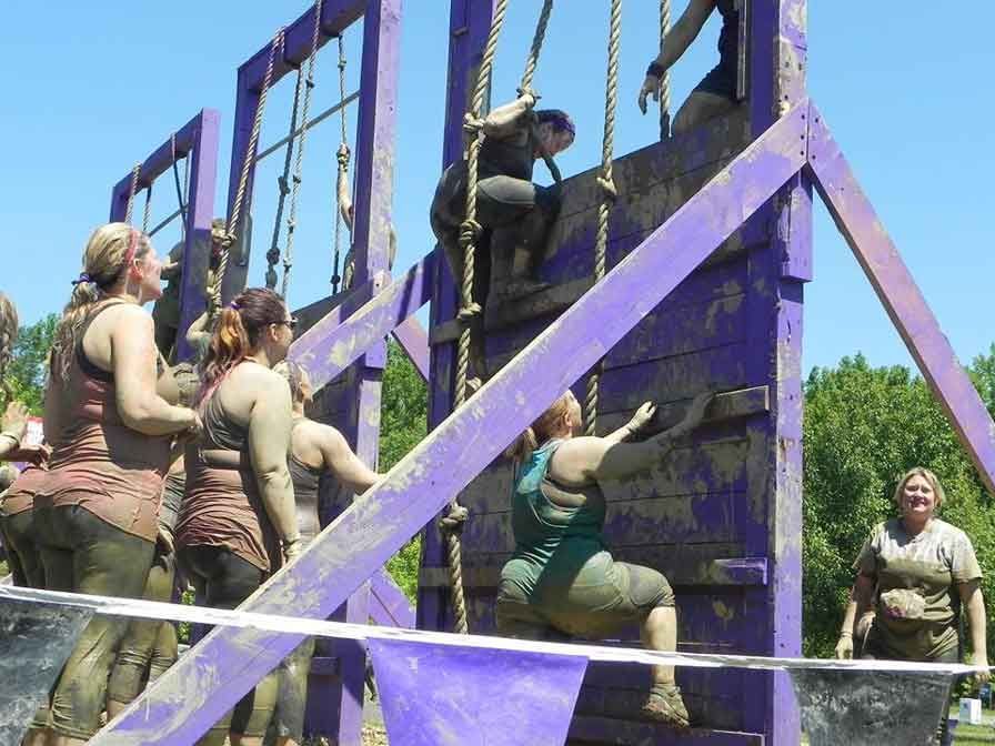 A group of women are climbing a purple wall