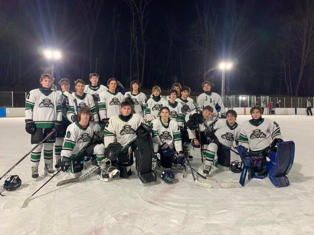 A group of hockey players are posing for a picture on the ice.