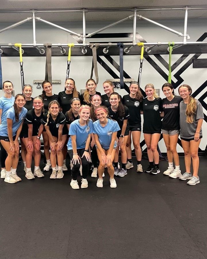 A group of young women are posing for a picture in a gym.