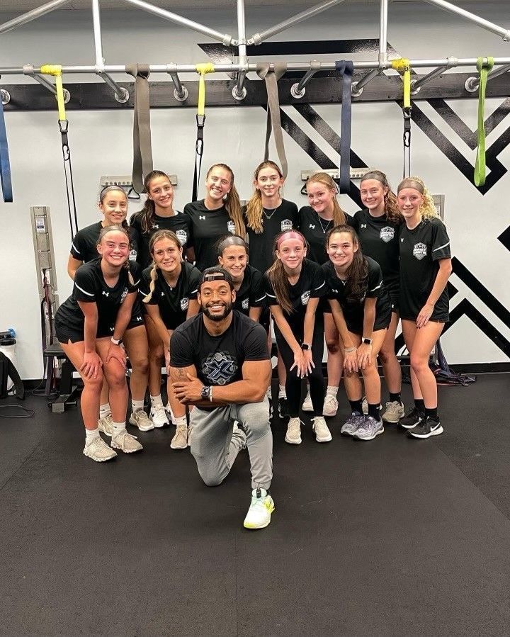 A group of people are posing for a picture in a gym.