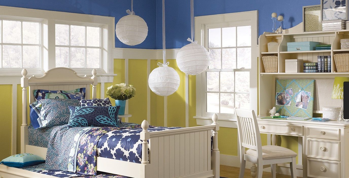 A bedroom with blue and yellow walls and a white bed