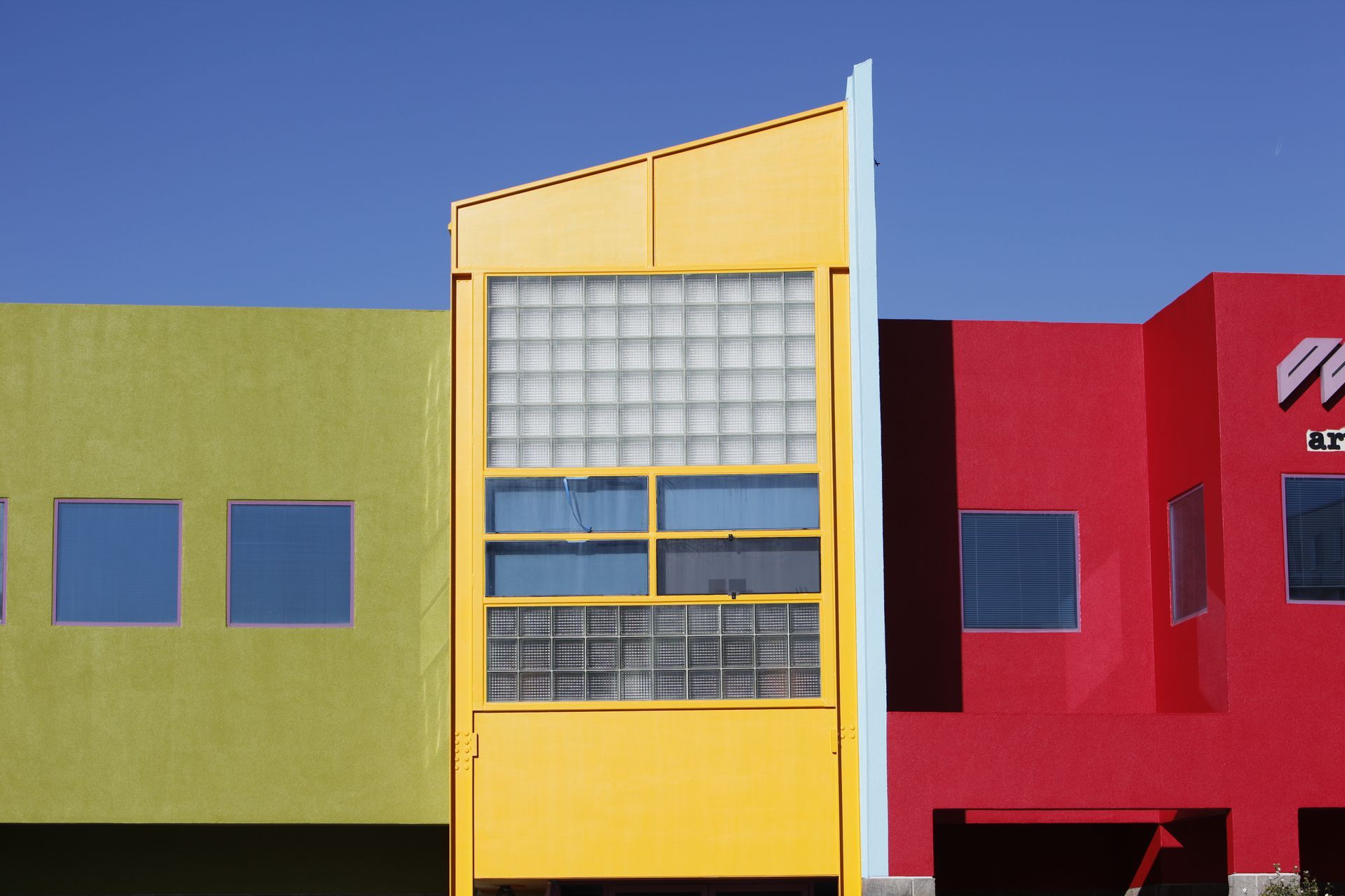 A yellow building is next to a green building and a red building