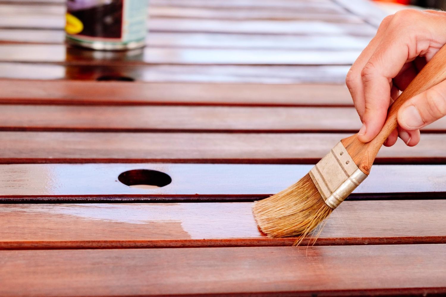 A person is painting a wooden table with a brush.