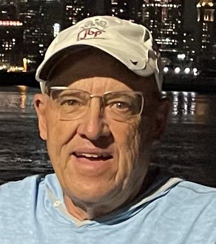 A man wearing a hat and glasses is smiling for the camera.