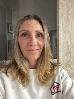 A woman is taking a selfie in front of a mirror while wearing a white sweatshirt.