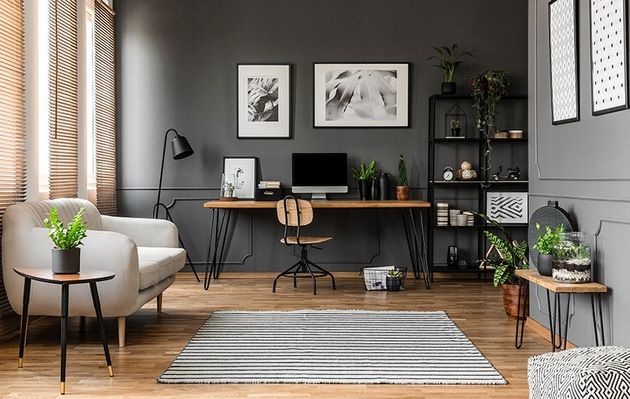 Modern home office with desk, computer, chair, gray walls, plants, and a striped rug