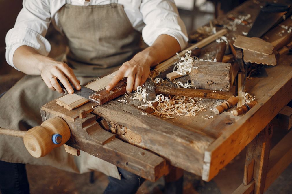 a man is carving a piece of wood on a wooden workbench