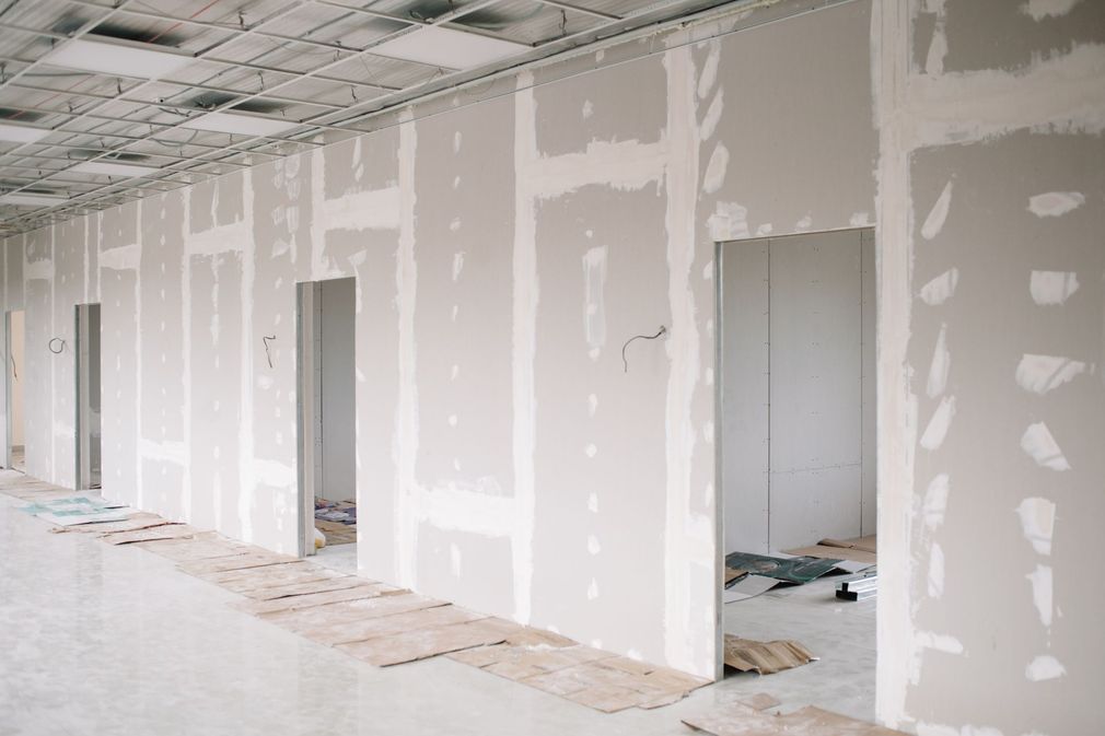 a long hallway with drywall walls and doors in a building under construction