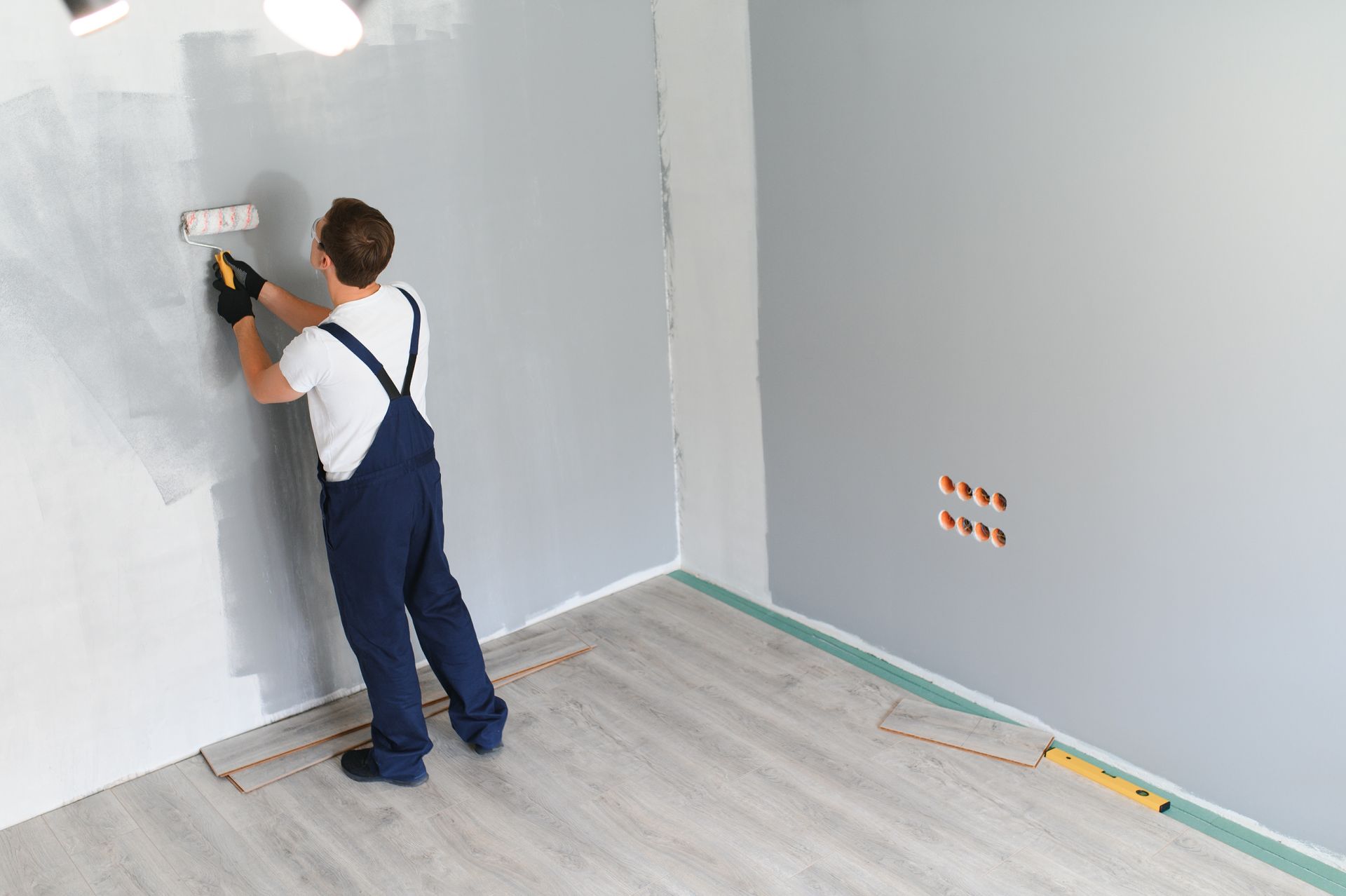 A man is painting a wall with a paint roller.