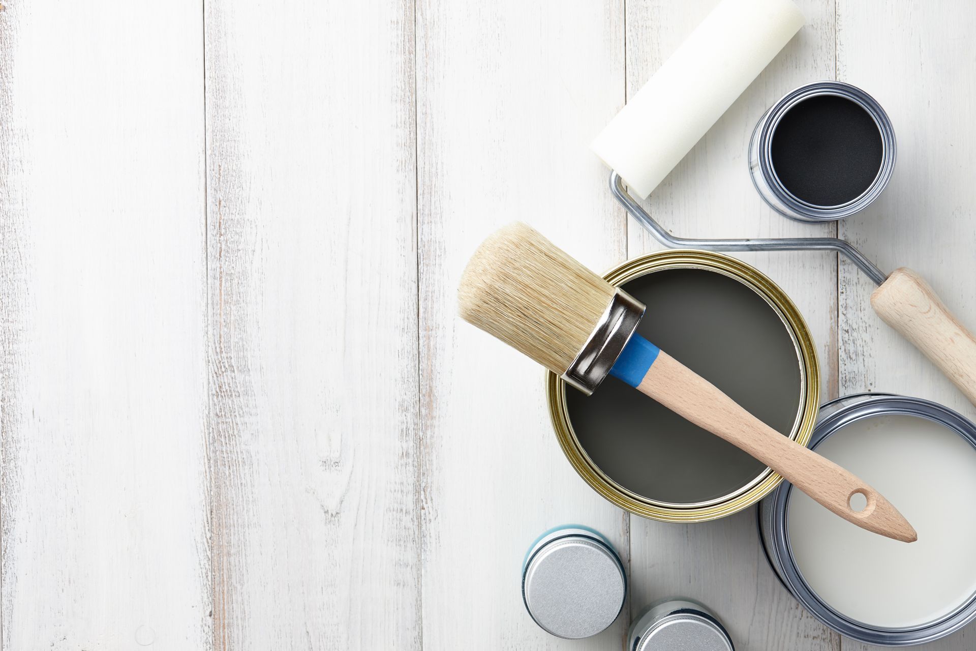 a can of paint and a brush on a wooden table.