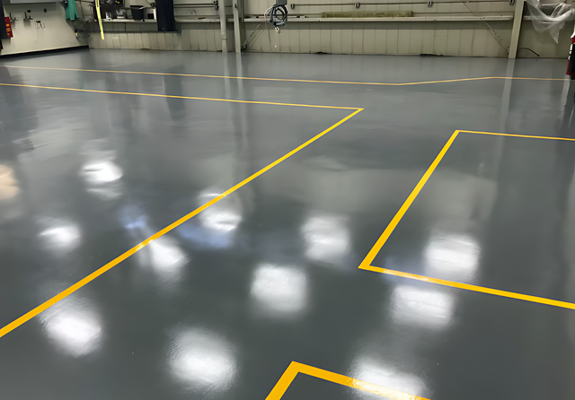 A warehouse with a gray floor and yellow lines on it.