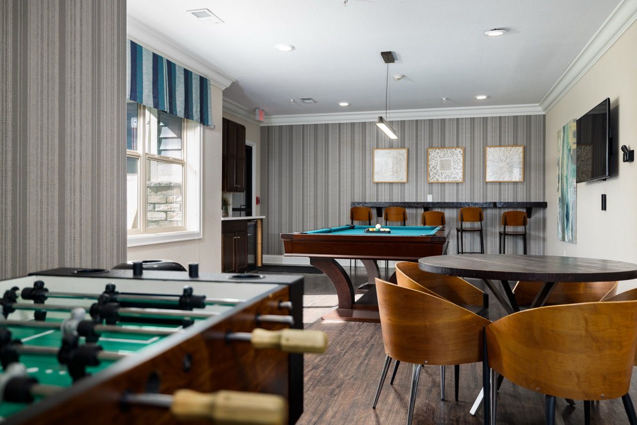 Indoor community lounge with pool table, foosball, and seating.